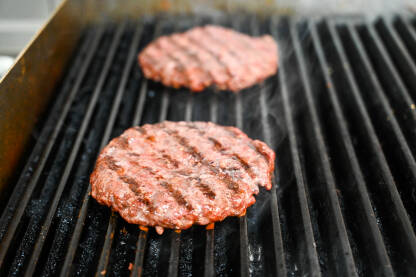 AK1_3021 (2) Pečenje hamburgera na roštilju s vrućim ugljenom. Ukusno mljeveno meso se priprema na roštilju. Kuhanje sirovih pljeskavica za hamburger.