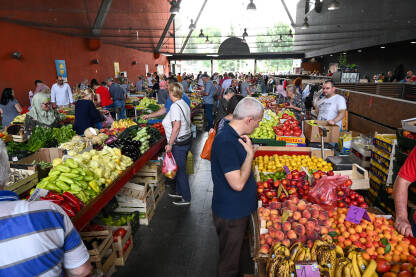Ljudi kupuju svježe povrće i voće na pijaci. Ljudi kupuju svježe povrće i voće na pijaci. Grupa ljudi na tržnici u kupovini. Kupci kupuju hranu.