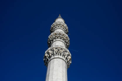 Minaret pored džamije. Avion prolazi iznad munare. Džamija u Ankari, Turska.