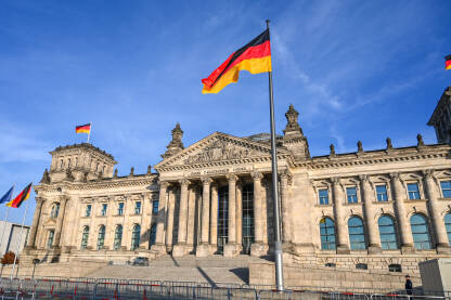 Bundestag, Berlin, Njemačka Bundestag, Berlin, Njemačka. Njemačka nacionalna zastava se vijori na jarbolu ispred zgrade Reichstaga u Berlinu. Državni i nacionalni simbol.