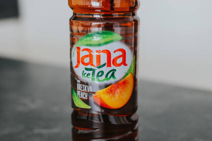 Jana ledeni čaj od breskve na sivoj podlozi, bijela pozadina