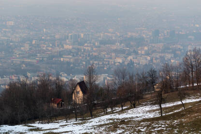Seosko imanje pored Banjaluke Kuća i voćnjak na brdu i grad Banja Luka u pozadini u izmaglici