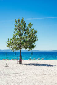 Plaža Šljunčana plaža sa suncobranima, ležaljkama i pogledom na ostrva Hvar i Brač.