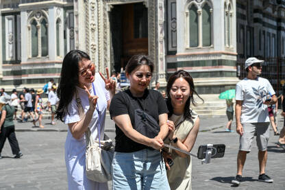Turistkinje iz Azije prave selfie na trgu. Turistkinje iz Azije prave selfie na trgu. Djevojke koriste mobilni telefon i slikaju se.
