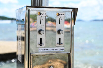 Tuševi na naplatu na plaži Javni tuševi na naplatu na plaži. Tuširanje se naplaćuje.