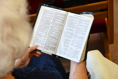 Starija žena moli u adventističkoj crkvi. Starija žena moli u crkvi. Žena drži knjigu tokom molitve. Vjernici se mole.