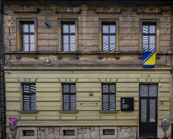 Zgrada Muzeja optičkih iluzija u Sarajevu. Na fasadi se nalazi tabla sa nazivom muzeja, a na prozorima su postavljene dekorativne grafike sa optičkim motivima.