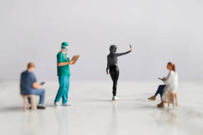 Figurice doktora posmatraju figuricu djevojke koja pravi selfie.