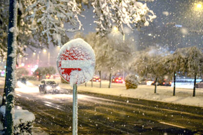 Obilne snježne padavine noću prekrivaju saobraćajni znak. Saobraćajni znak prekriven snijegom zimi.