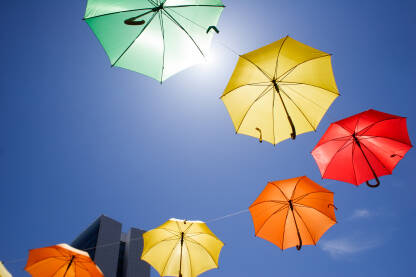 Kišobrani različitih boja, zakačeni na žicu iznad ulice. Umjetnička instalacija. Intervencija u prostoru.