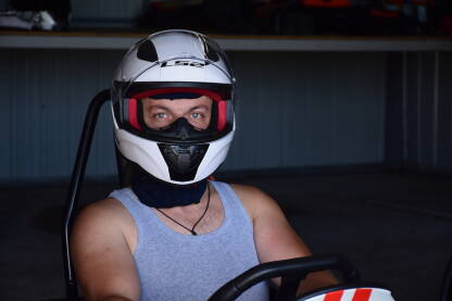 Muškarac sa kacigom za karting Muškarac sa kacigom na glavi spreman za karting vožnju. Samouvjerenog pogleda iako je ovo njegova prva vožnja. Ono što ne vidite jesu njegova kolica. Auto je prilagođen je na ručne komande.