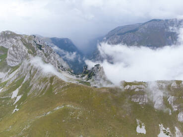 Planina u magli, snimak dronom. Durmitor, Crna Gora. Planina u magli, snimak dronom. Oblačan dan u planinama. Litice i stijene na vrhu planinskog lanca. Oblaci prelaze planinski prijevoj. Durmitor, Crna Gora.
