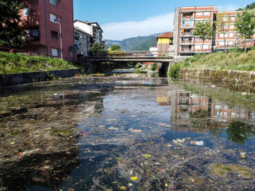 Zagađena rijeka u gradu Zagađena rijeka u gradu. Smeće u rijeci. Otpad pluta u vodi. Ekološki problem. Plastične vrećice, boce i smeće bačeno u rijeku.