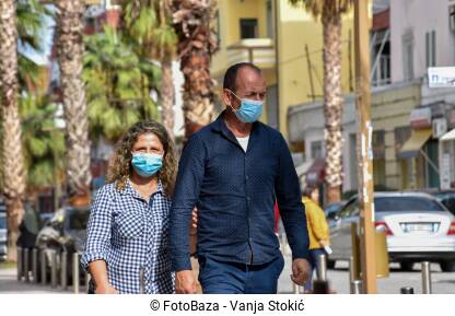 Ljudi šetaju sa maskama Par srednjih godina hoda ulicom sa maskama na licu, zbog pandemije virusa korona. Muškarac i žena šetaju ulicama Drača, Albanija.