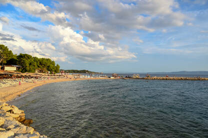 Makarska, Hrvatska. Ljudi uživaju na plaži uz more. Turisti Makarska, Hrvatska. Ljudi uživaju na plaži uz more. Turisti na pješčanoj plaži tokom zalaska sunca. Godišnji odmor.