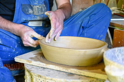 Majstor radi s glinom na grnčarskom kolu. Čovjek obrađuje glinu. Majstor pravi glinenu zdjelu. Obrada gline. Proizvodnja keramičkog posuđa od prirodnih materijala.