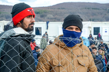 Izbjeglice i migranti iza bodljikave žice u kampu. Izbjeglice i migranti iza bodljikave žice u kampu. Kamp za migrante u Bihaću, Bosna i Hercegovina. Tražitelji azila.