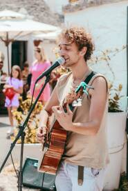 Ulični pjevač sa gitarom u ruci. Svira i pjeva na ulici i zabavlja prolaznike.