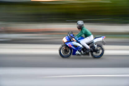 Vozač motora se brzo kreće na motociklu ulicom. Zamagljeni čovjek se brzo kreće na motociklu ulicom. Vožnja motorom po gradu. Vozač motocikla.