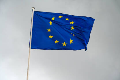 Zastava Evropske unije Zastava EU se vijori na vjetru sa tamnim oblačnim nebom u pozadini. EU zastava na jarbolu.