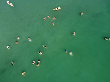 Turisti plivaju u moru. Grupa ljudi se zabavlja u vodi tokom ljetnih praznia. Ljudi uživaju u moru.