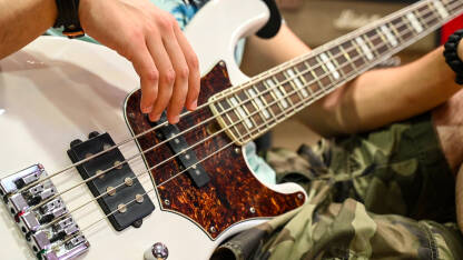 Mladi muzičar svira električnu gitaru Mladi muzičar svira električnu bas gitaru na bini. Čovjek svira bas gitaru s bendom na koncertu, krupni plan. Bas gitarista svira na festivalu. Muzički instrument