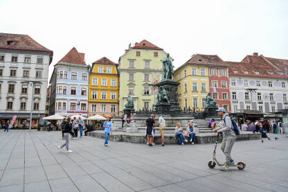 Graz, Austrija: Grupa ljudi na glavnom trgu u centru grada. Graz, Austrija: Grupa ljudi na glavnom trgu u centru grada. Historijske zgrade na glavnom trgu ili Hauptplatzu. Stari grad Graz. Erzherzog-Johann-Brunnen fontana.