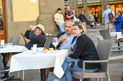 Turisti piju piće u kafiću Turisti piju piće na terasi restorana. Ljudi sjede u kafiću.
