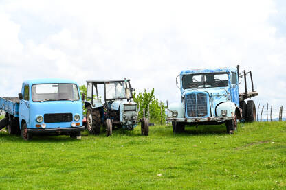 AK1_4165 Stari i zahrđali kamioni i traktor na livadi. Napušteni automobili u prirodi.