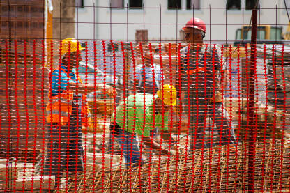 Građevinski  radnici na gradilištu, u zaštitnoj opremi.