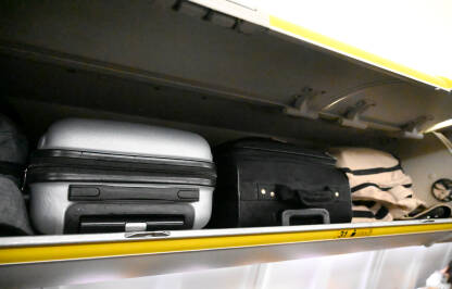 Putnički koferi u kabini aviona. Prtljag putnika u avionu. Putne torbe. Ručni prtljag.