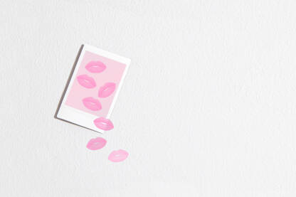 Instax fotografija s poljupcima visi na zidu, a motiv poljubaca izlazi izvan granica okvira.