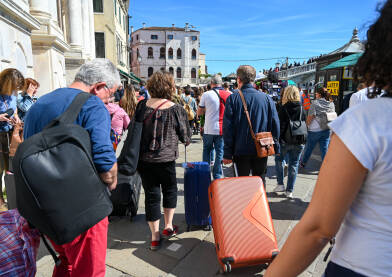 Turisti s torbama i koferima Turisti s torbama i koferima u gradu. Gužva na ulici u Veneciji, Italija. Turisti istražuju grad.