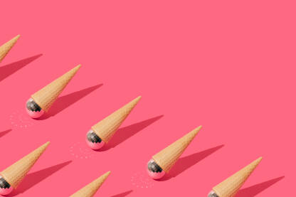 Korneti za sladoled s disko kuglama na ružičastoj pozadini.