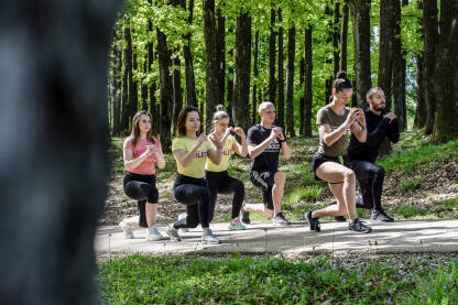 Trening na otvorenom Trening na otvorenom. Grupa ljudi vježba u prirodi. Vježba iskorak.