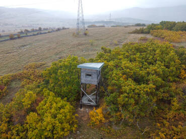 Drveni lovački zaklon u šumi, pogled iz zraka. Lovački osmatračnički toranj. Lovačka čeka u šumi, snimak dronom.