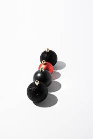 Četiri sjajne ukrasne kuglice poredane na bijeloj pozadini. Novogodišnja, božićna čestitka.