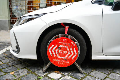 Nepropisno parkiranje Parkirani automobil sa blokadom na gumama. Blokada točkova zbog nepropisnog parkiranja na ulici.