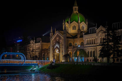 Akademija likovnih umjetnosti u Sarajevu snimljena noću, zajedno s osvijetljenim mostom Festina lente i refleksijama na vodi.