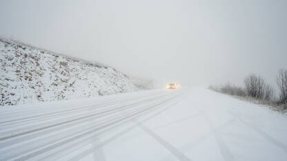 Vožnja vozila po snježnoj i skliskoj cesti. Automobili na asfaltnoj cesti pokrivenoj snijegom. Vožnja u zimskim uslovima.