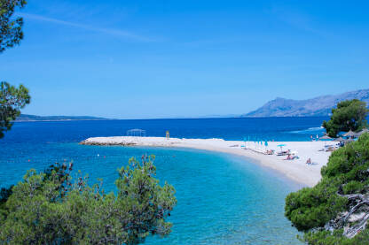 Plaža Šljunčana plaža sa suncobranima, ležaljkama i pogledom na ostrva Hvar i Brač.
