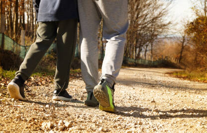 Čovjek i dječak koračaju makadamskim putem.