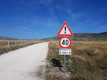 Saobraćajni znakovi, makadam Saobraćajni znakovi koji označavaju ograničenje brzine kretanja vozila na 40 km/h i opreznu vožnju zbog kretanja po makadamskoj cesti u dužini od 15.000 m, tj. 15 km