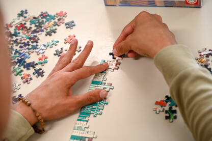 Dječak slaže puzzle. Igra. Dječak slaže puzzle. Igra. Ruke slažu mnogo dijelova puzzli.
